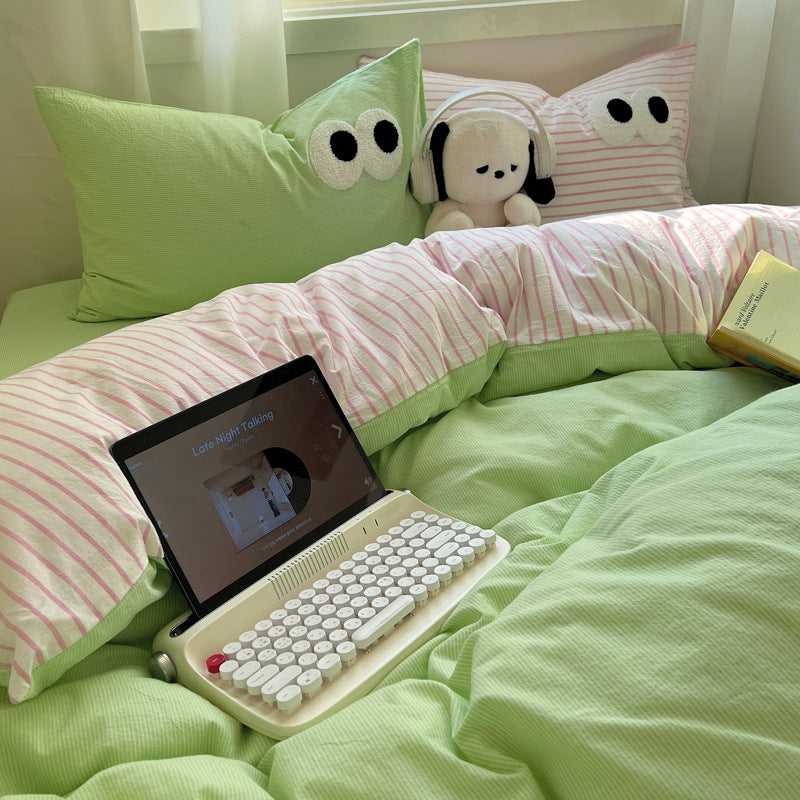 Bedding set with green and pink striped pillows and playful eyes